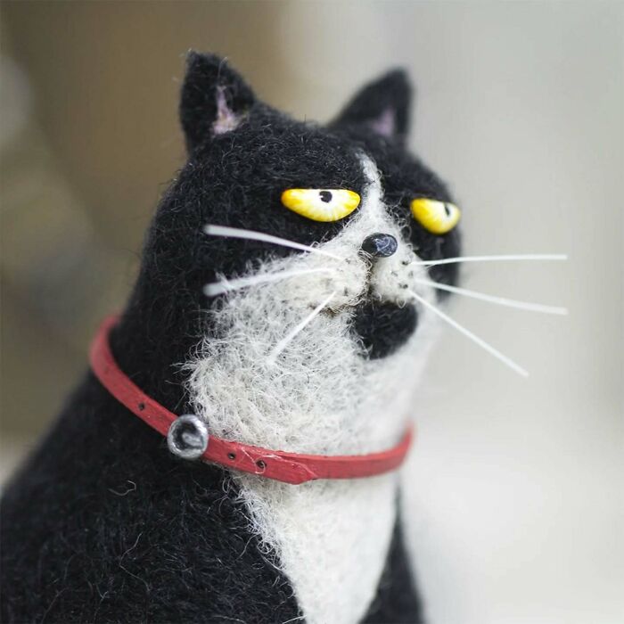 Funny-looking animal doll by Georgian artist, resembling a cat with a red collar and yellow eyes.