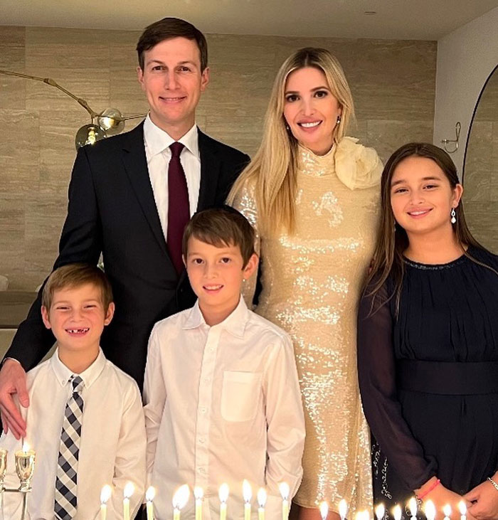 Family dressed elegantly, gathered around lit candles for a celebration, emphasizing elegance and class in their attire.