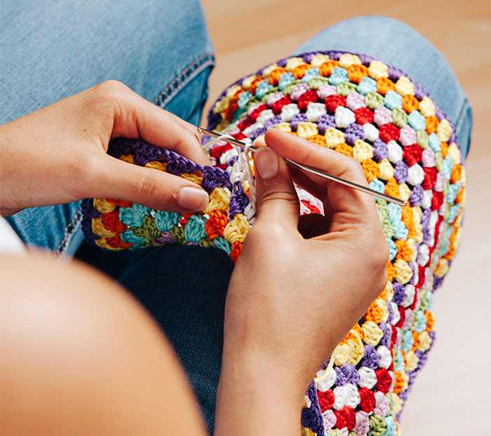 Person crocheting a colorful handmade gift with a crochet hook, focusing on intricate details.