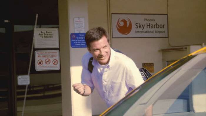 A man at an airport, smiling and heading toward a taxi, representing beloved shows from thrillers to comedy.