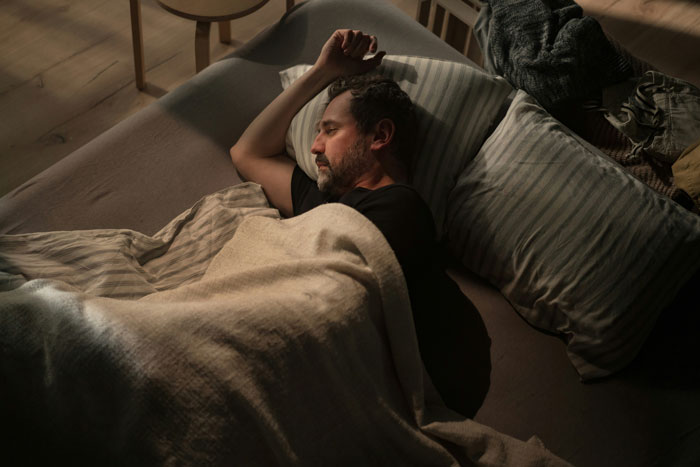 Man asleep on a couch, covered with a blanket, evoking a story about family secrets.