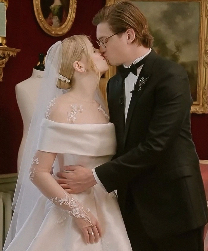 Bride in viral wedding dress kisses groom, with elegant decor in the background.