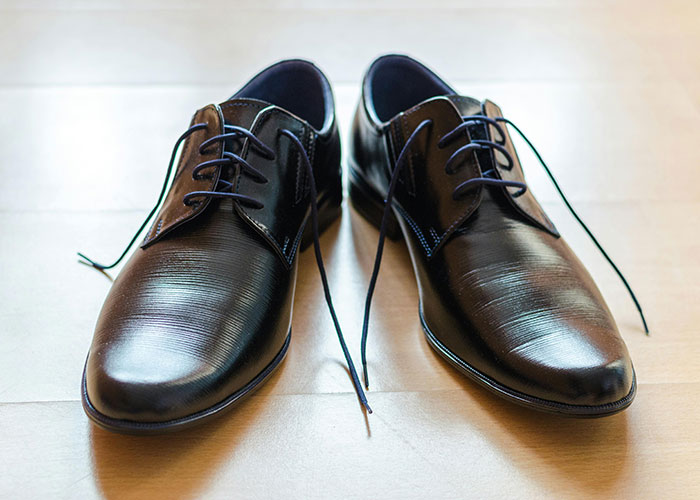 Black formal shoes on a wooden floor, symbolizing preparation for awkward job interviews.