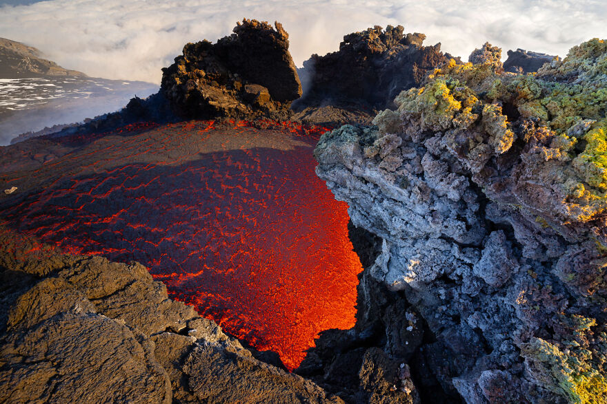 A vibrant red lava pool amid volcanic rock formations, showcasing award-winning wildlife photography.