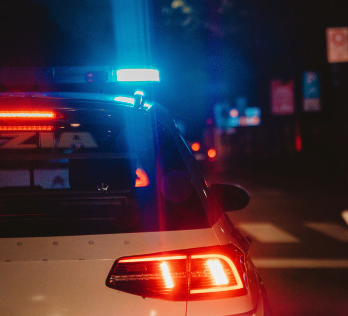 Police car with flashing lights at night, highlighting officer-related scenarios.