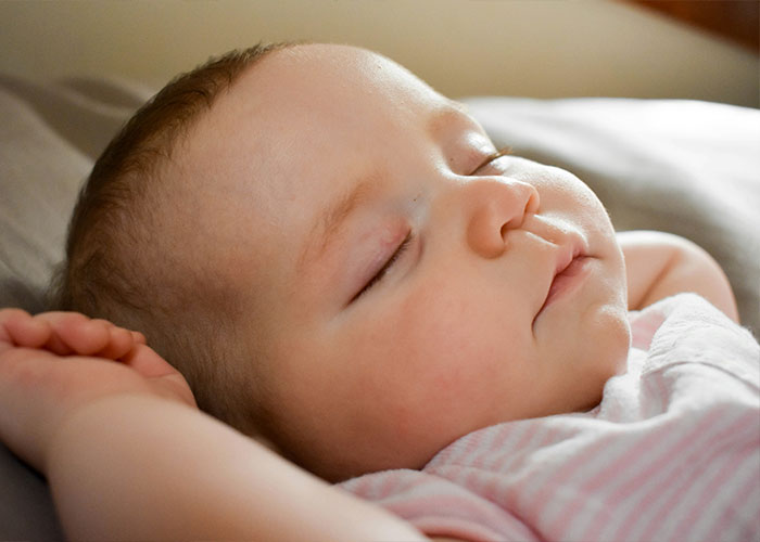 Sleeping baby lying peacefully on a bed, symbolizing tranquility amidst family tensions involving a Canadian woman.