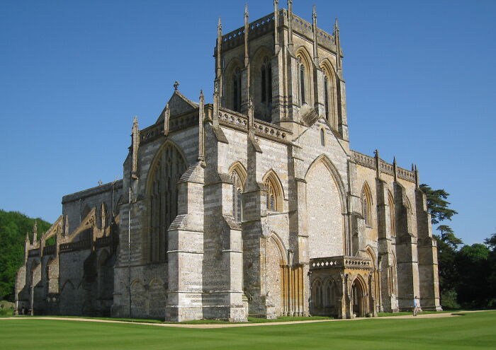 Gothic-style church with intricate stonework under a clear blue sky, showcasing fascinating architectural details.