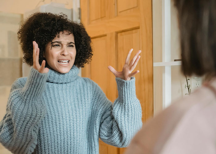 Canadian woman gesturing in frustration, wearing a blue sweater, indoors.