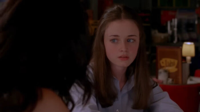 Young woman in a diner, looking concerned, from a beloved show watched millions of times.