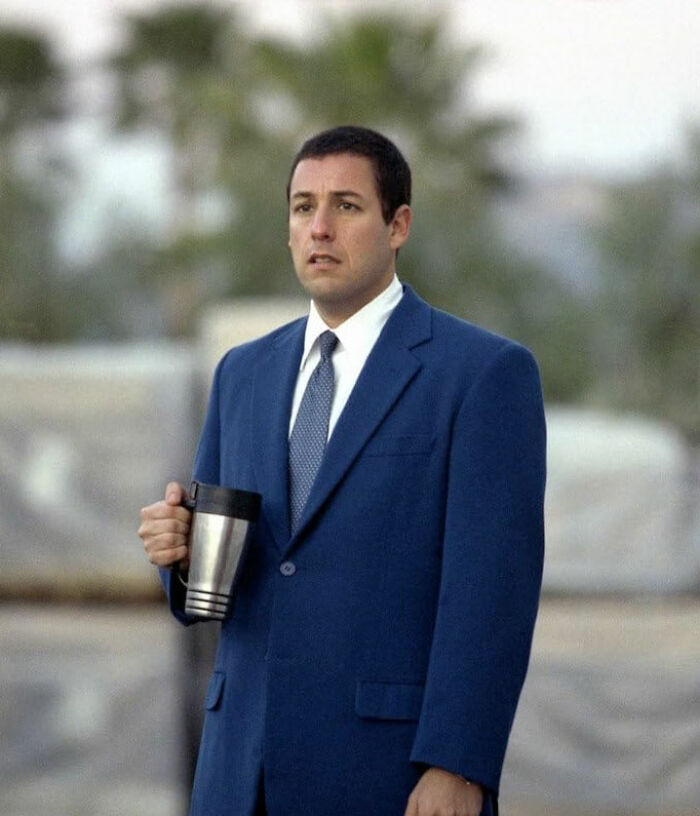 Actor in a blue suit holding a coffee mug, showcasing talent despite being pigeonholed in roles.