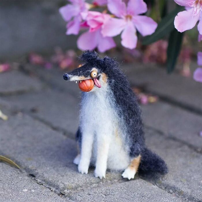 Funny-looking animal doll with wild eyes and fluffy fur, created by a Georgian artist, amidst pink flowers.