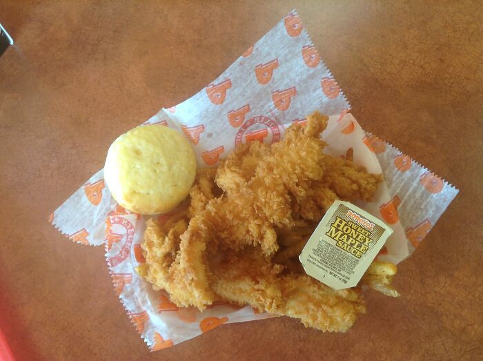 Fried chicken tenders with honey sauce and biscuit from a popular fast-food chain.