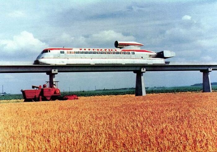 Futuristic train on elevated track above a wheat field, showcasing historical inventions ahead of their time.