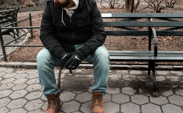 Man sitting alone on a park bench with folded arms, representing untold family stories.