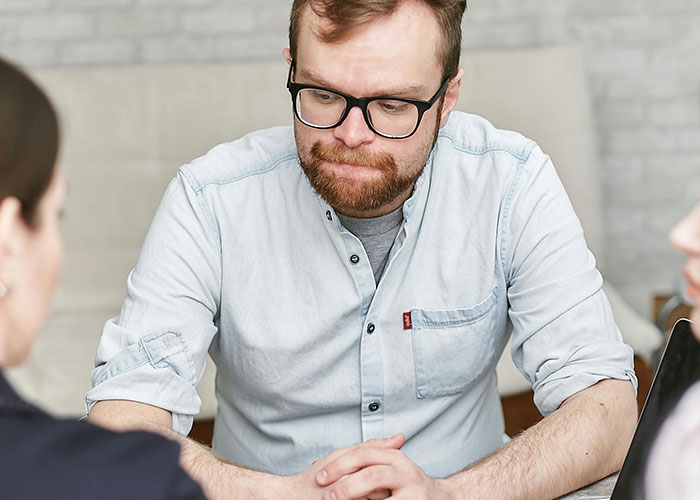 Man in glasses and a light shirt at a table during an awkward job interview.