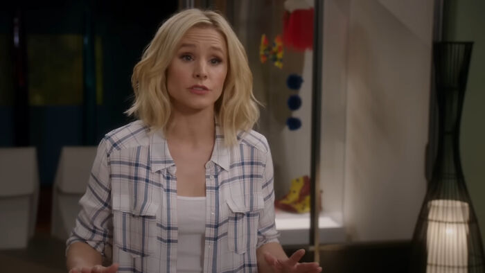 Woman in a casual plaid shirt standing indoors, part of a beloved show enjoyed by viewers multiple times.