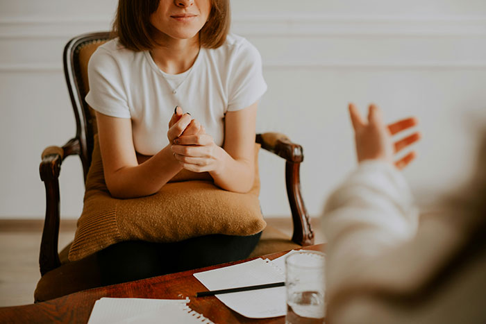 Person sitting in a chair, engaging in conversation, illustrating real-life quality hacks in an informal setting.