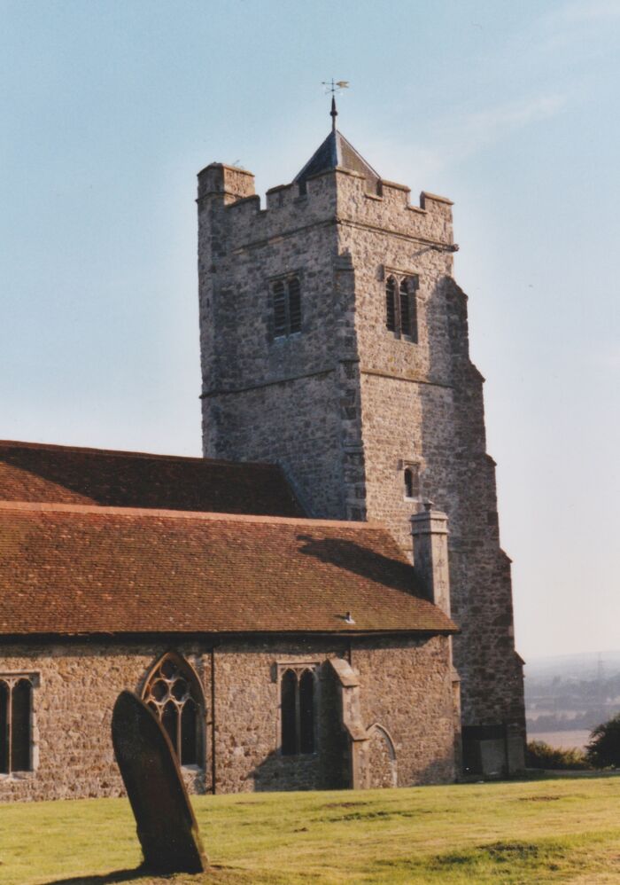 Stone church with a tall tower and red roof basking in sunlight, illustrating fascinating church architecture.