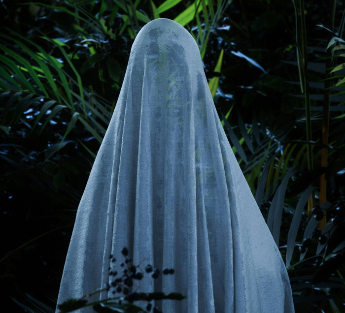 Ghostly figure draped in a sheet standing in a jungle, representing mysterious corruption in law enforcement.