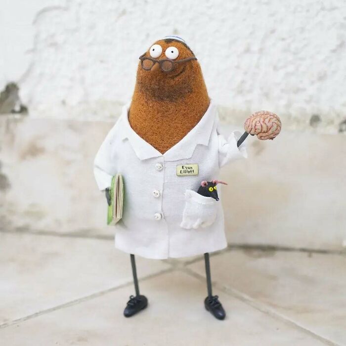 Strange art doll resembling a scientist, holding a brain, with glasses and a small rodent in its pocket.