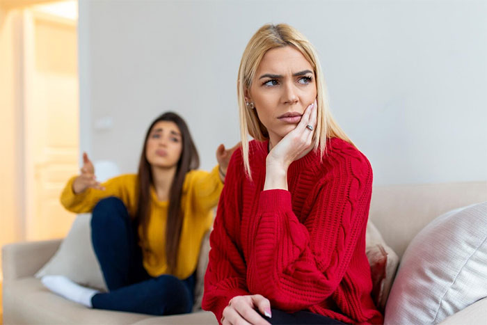 Two women on a couch; one looking upset, highlighting demands about a handmade gift.