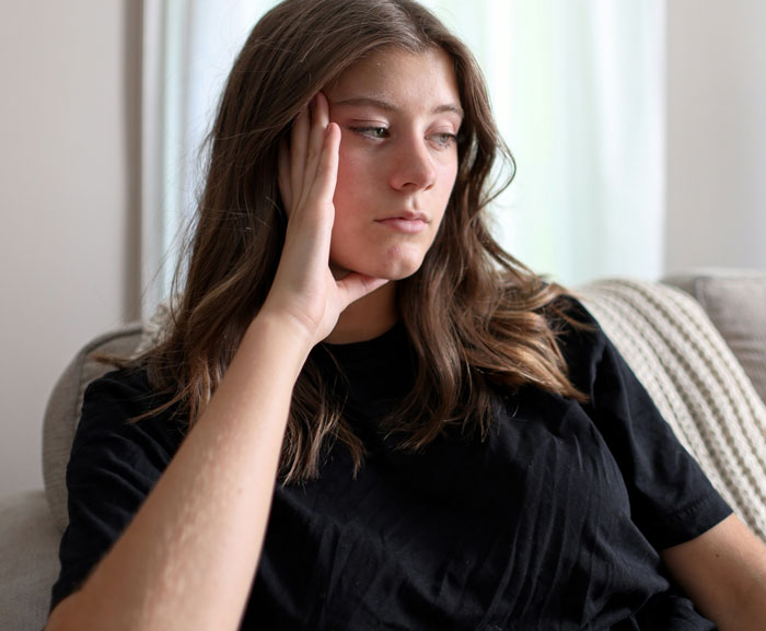 Woman contemplating on a couch, related to a "deadbeat" discussion turned success story.