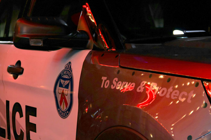 A police car with "To Serve & Protect" slogan reflecting lights, highlighting themes of concern and corruption in policing.