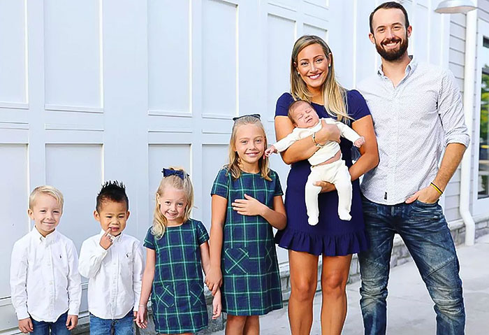 Family posing together outside, woman holding baby, children smiling, related to YouTubers Myka and James Stauffer.