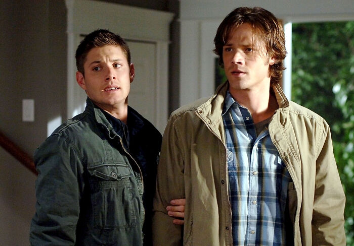 Two men in casual jackets sharing a moment indoors, linked to fascinating fan theories.