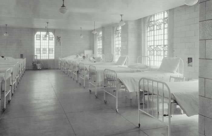 Monochrome image of a historical hospital ward with empty beds, conveying a family’s untold story.