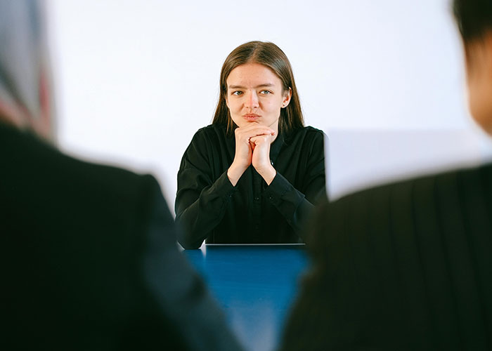 Young woman in a job interview, looking awkwardly at the interviewers.