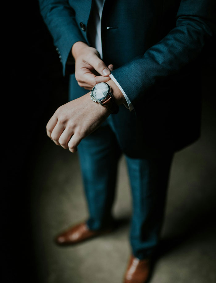 Person in a suit adjusting a watch, embodying real-life cheat codes for efficiency.