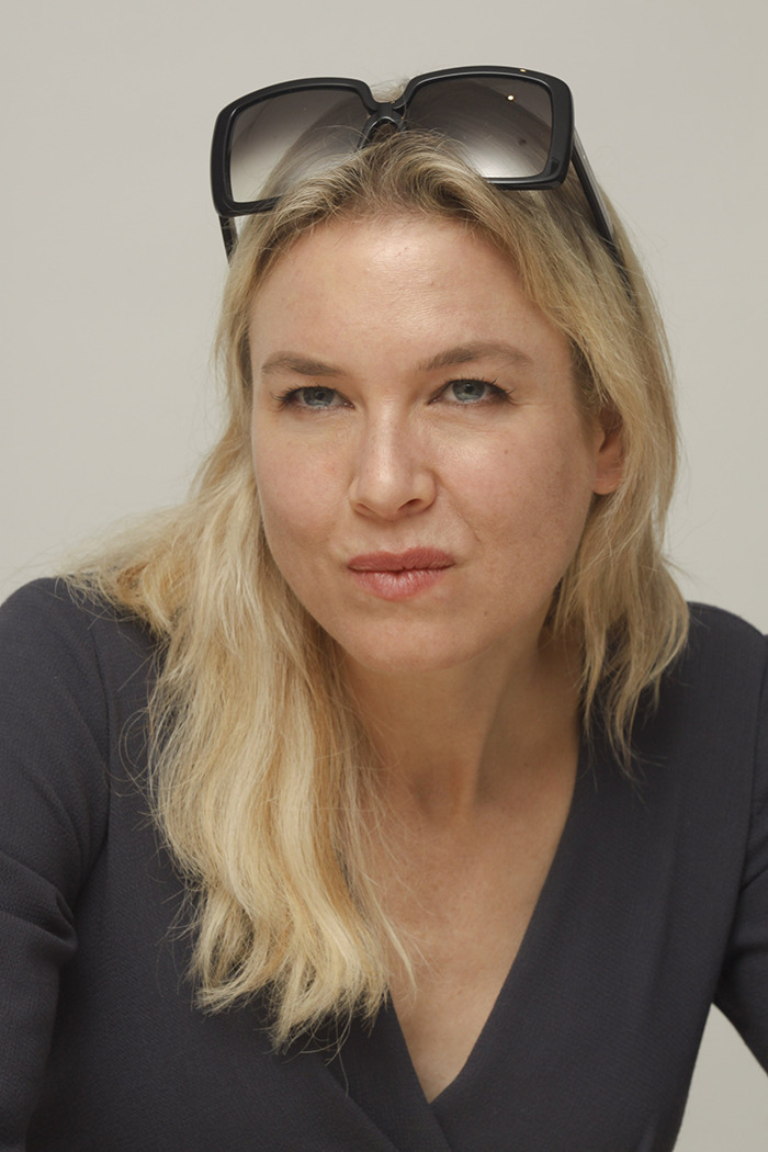 Blonde woman in a dark outfit, wearing black sunglasses on head, showcasing appearance changes.