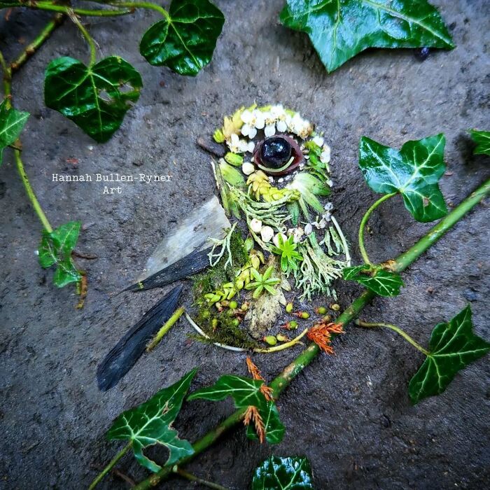 Animal portrait crafted from natural materials, featuring leaves and petals, surrounded by green foliage.