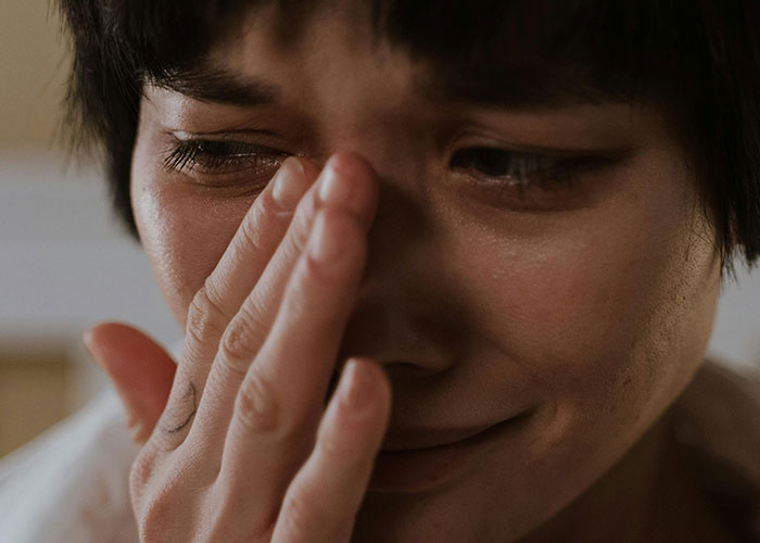 Person expressing awkwardness by covering their face, relating to job interview experiences.