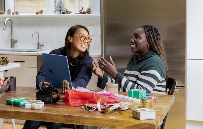 Two people in a kitchen exchanging smiles and conversation, surrounded by gifts and colorful wrapping, embodying real-life hacks.