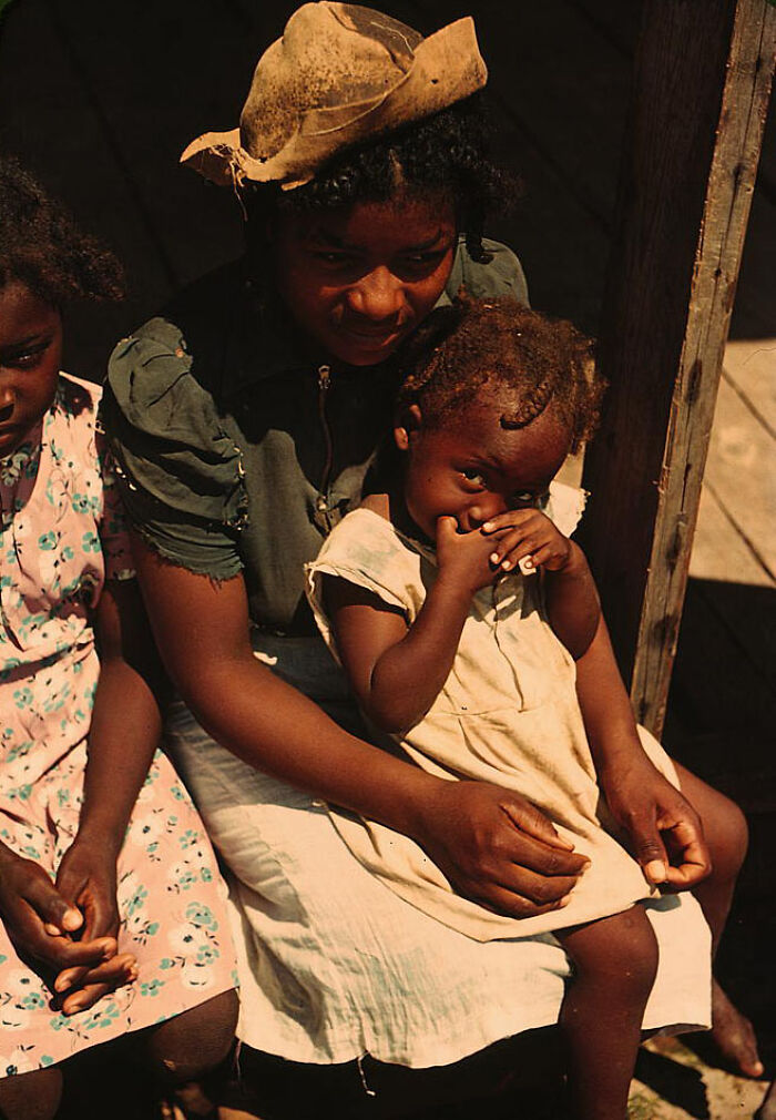 A mother and children in 1940 color photos, sitting together, the child resting on her lap.