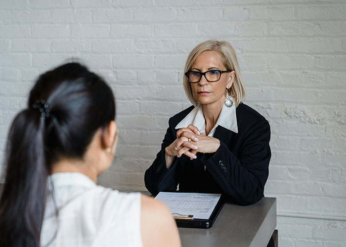 Job interview scene with interviewer in glasses listening seriously, creating an awkward atmosphere.