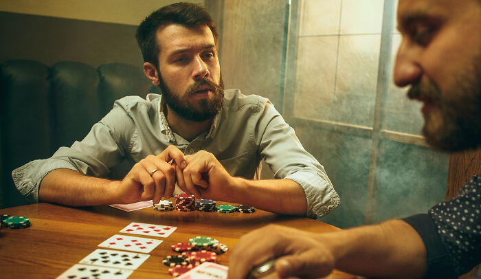 Two men playing poker, focused and intense, with chips and cards on the table, illustrating a moment of realization.