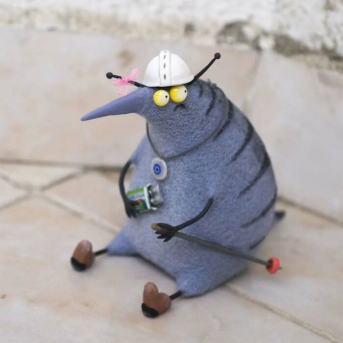 Funny-looking animal doll with a beak and helmet, designed by a Georgian artist, holding a small object.