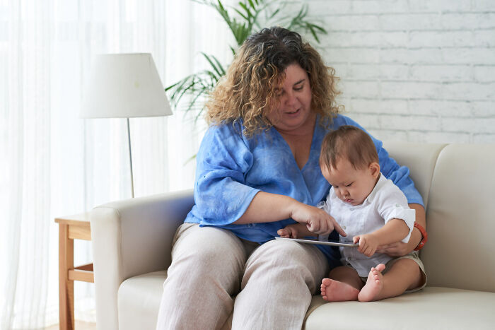 A parent and child sitting on a sofa, interacting with a tablet.