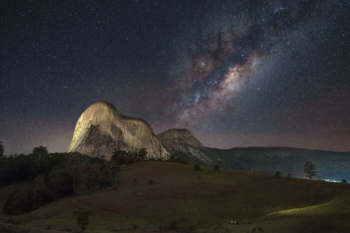 Starry sky with Milky Way over a mountain, showcasing stunning natural phenomena.