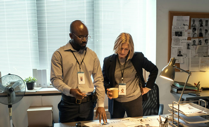 Detectives examining a case board and documents in an office, highlighting true crime cold cases.