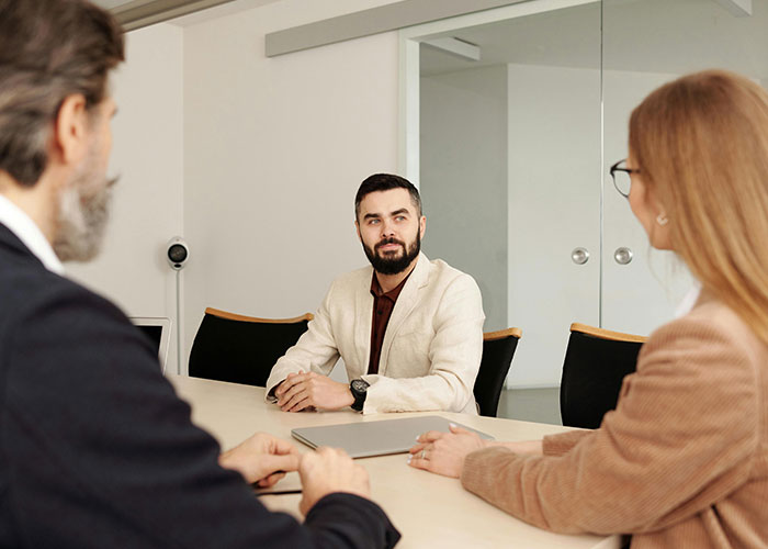 Job interview with three people sitting at a conference table in an office setting.