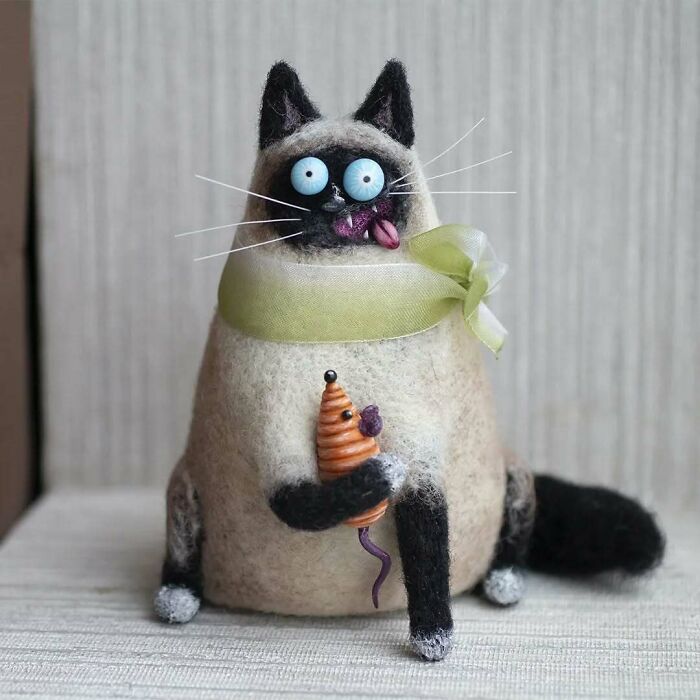 Strange art doll of a quirky animal with exaggerated features, crafted by a Georgian artist, holding a small toy.