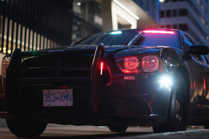 Police car with flashing lights on a city street at night.