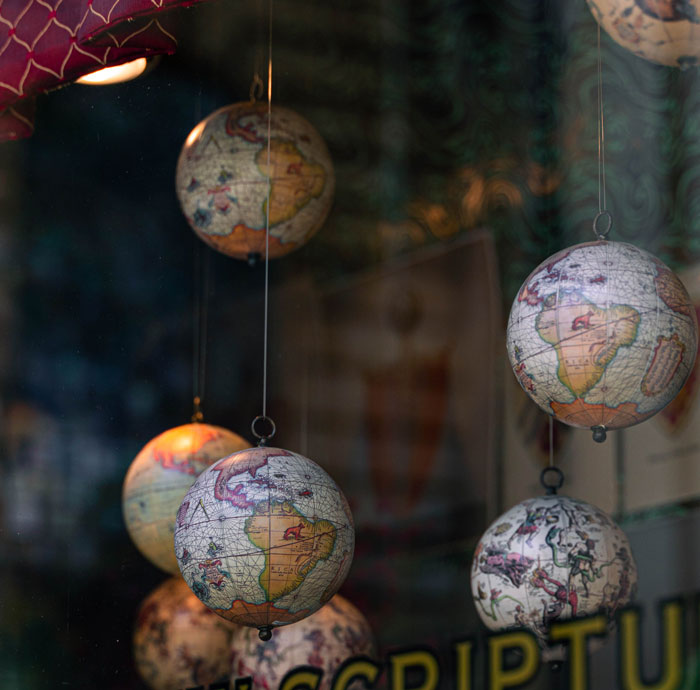 Globes hanging in a shop window, representing untold family stories.