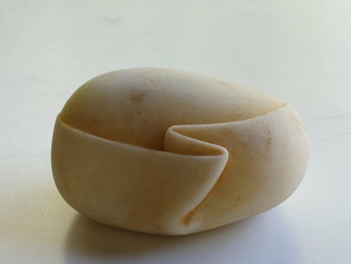 A smooth, curled stone sculpture resembling soft fabric, showcasing craftsmanship and defying physics.