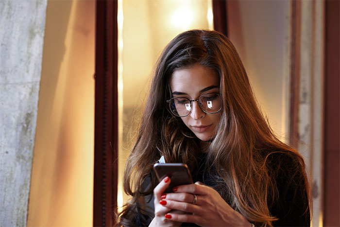 Woman with glasses using smartphone, planning a party.