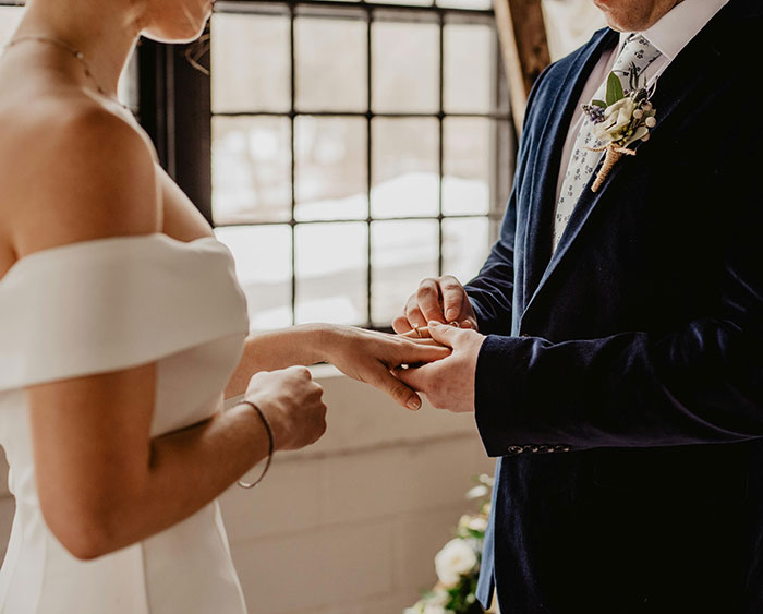 Bride and groom exchanging rings in a ceremony, highlighting an influencer's wedding scam.